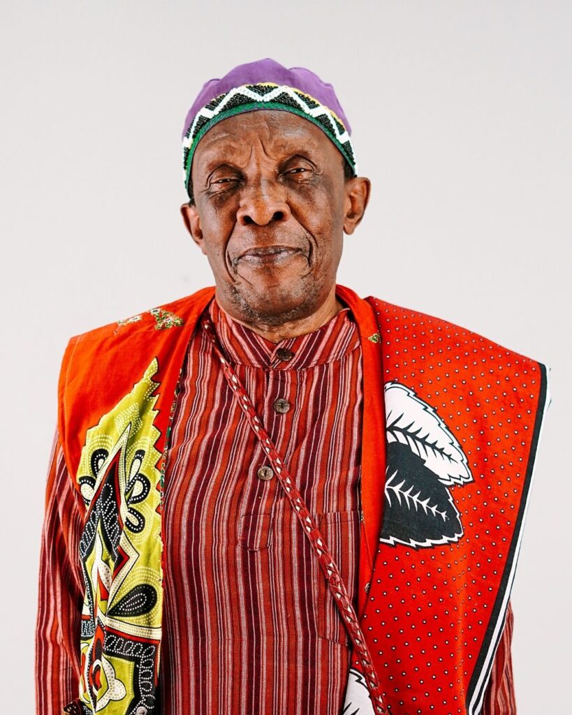 SUnset Jazz Melodies Artist from the Lineup Dr Madala Kunene in a bright red, yellow African inspired outfit. He will be performing in 6 Decemeber at the Sunset Jazz Melodies festival at Albert Falls Dam